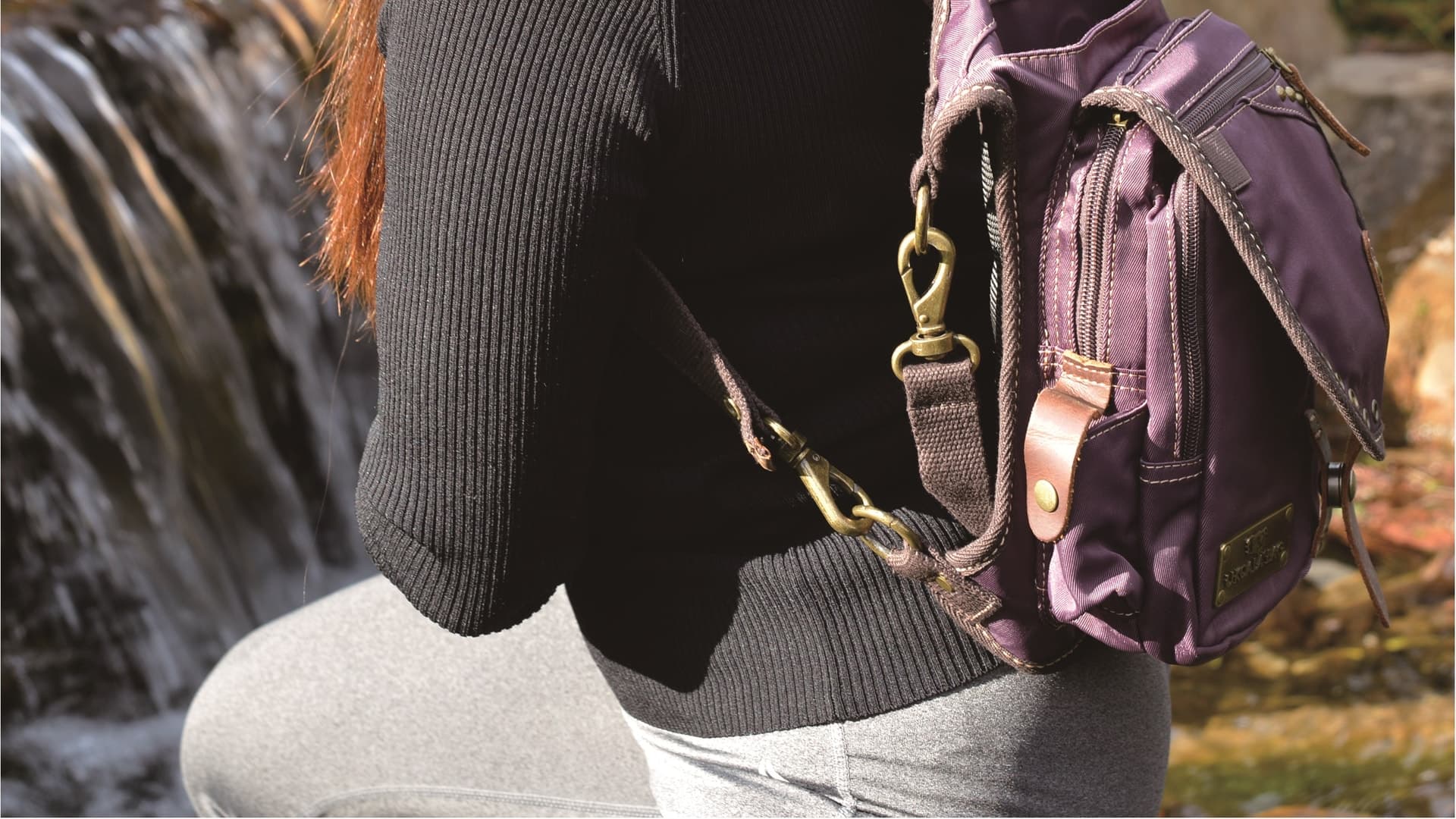 Real purple Ukoala bag worn close to the body beside a sunlit waterfall