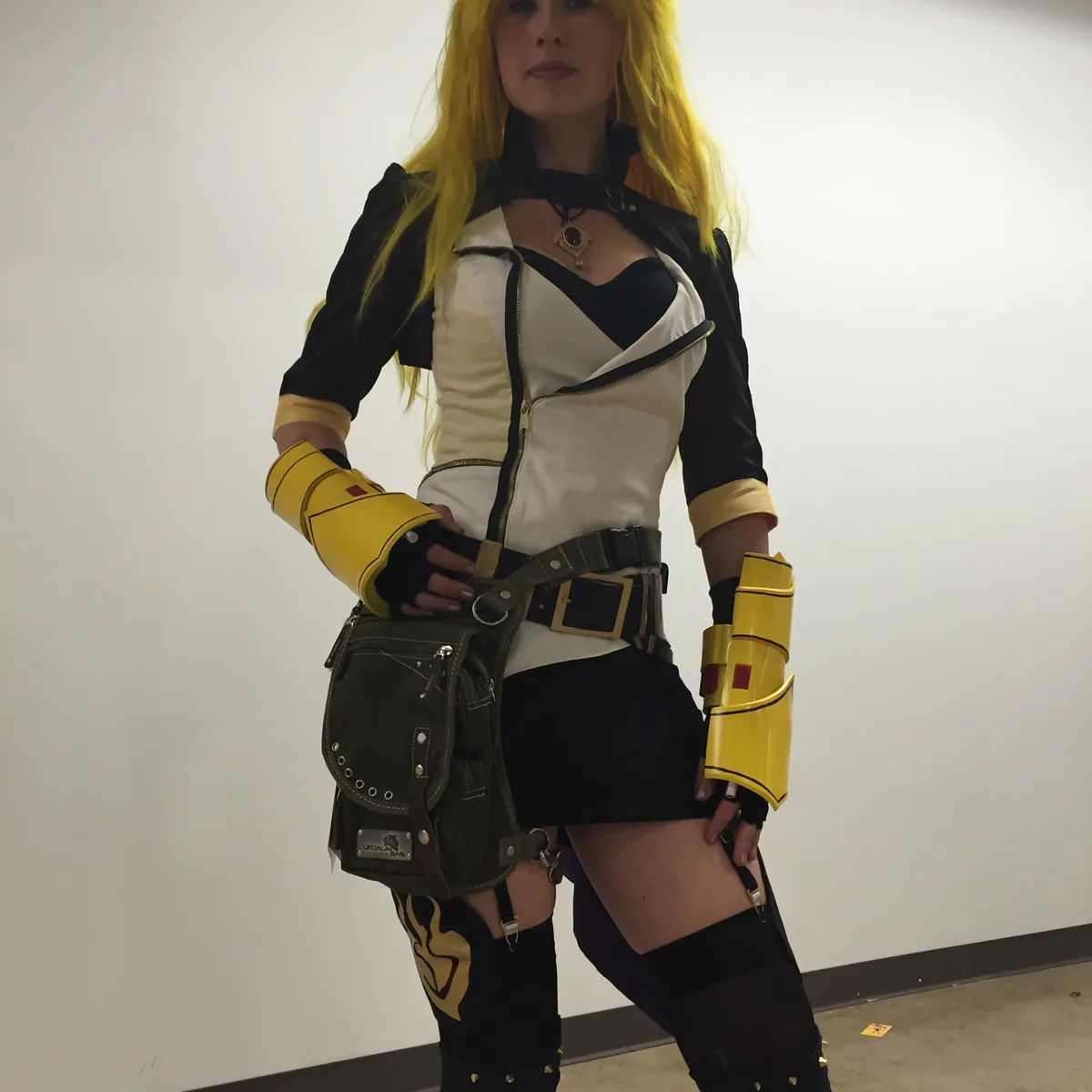 Cosplayer in a yellow-and-white costume wearing an olive Ukoala bag on the thigh at a convention