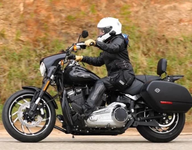 Motorcyclist in a white helmet riding a black cruiser with a Ukoala bag at the hip