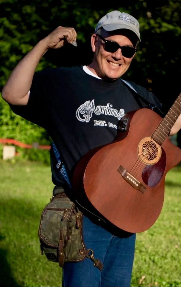 Guitarist at an outdoor show flexing with a camo Ukoala bag worn on the thigh