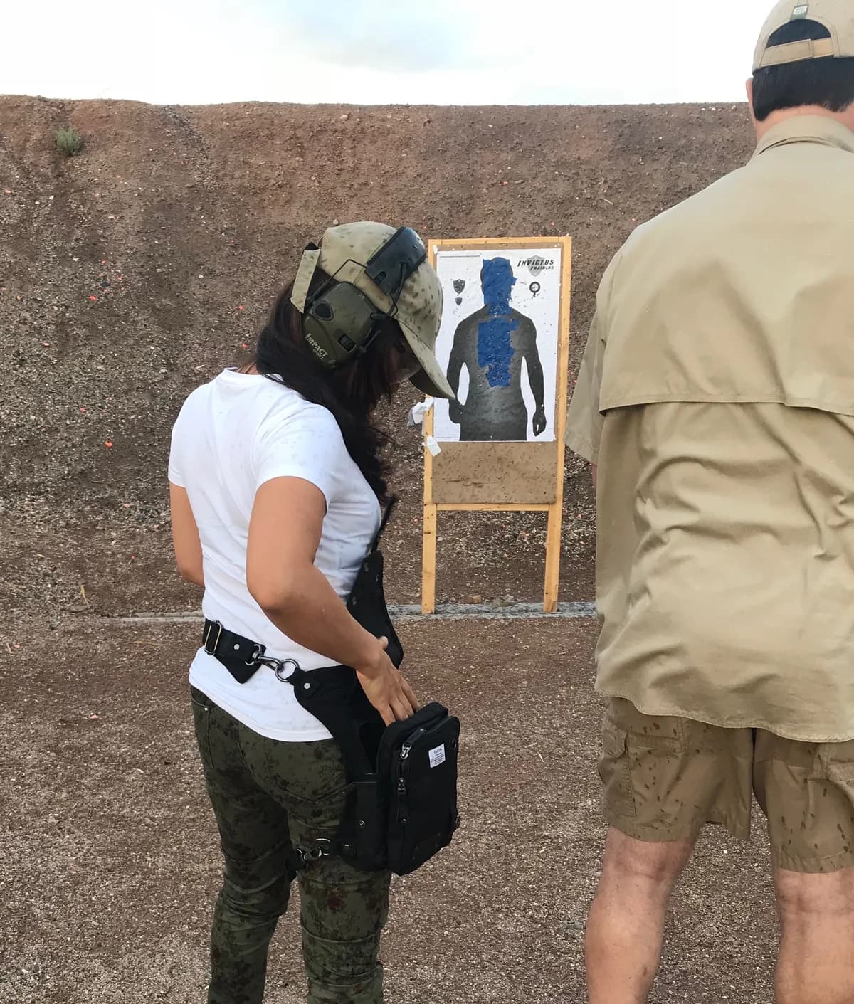 Shooter reviewing a target at an outdoor range with a Ukoala bag worn on the hip