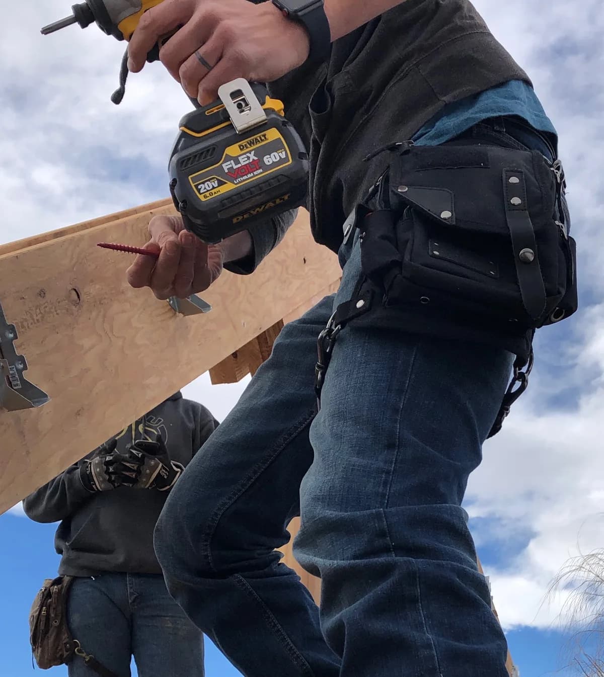 Builder driving screws into a board with a black Ukoala bag strapped to the thigh