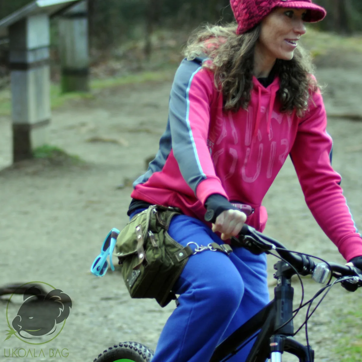 Mountain biker smiling mid-ride with a camo Ukoala bag strapped at the hip